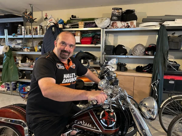 Renaud assis sur une Harley-Davidson à la peinture personnalisée, dans l'atelier
